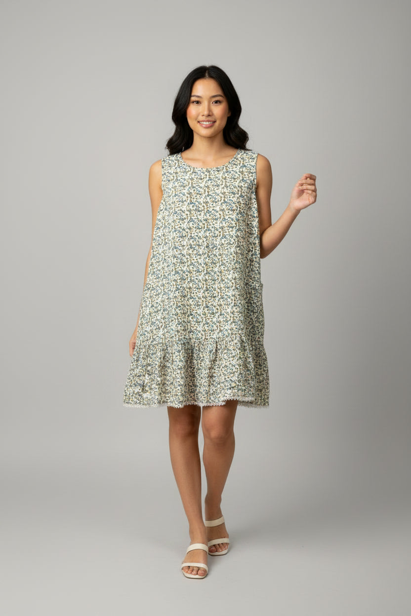 A sleeveless tiered ruffle dress with a dense small floral print in blue, green, and yellow on a cream background, \
