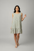 A sleeveless tiered ruffle dress with a dense small floral print in blue, green, and yellow on a cream background, \